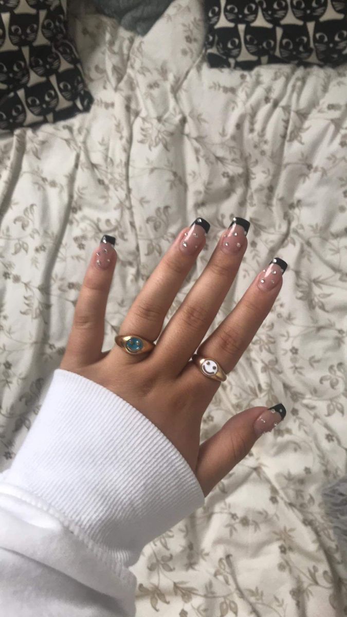 Chic French Tip Nail Design with Glossy Black Tips and Unique Rings.