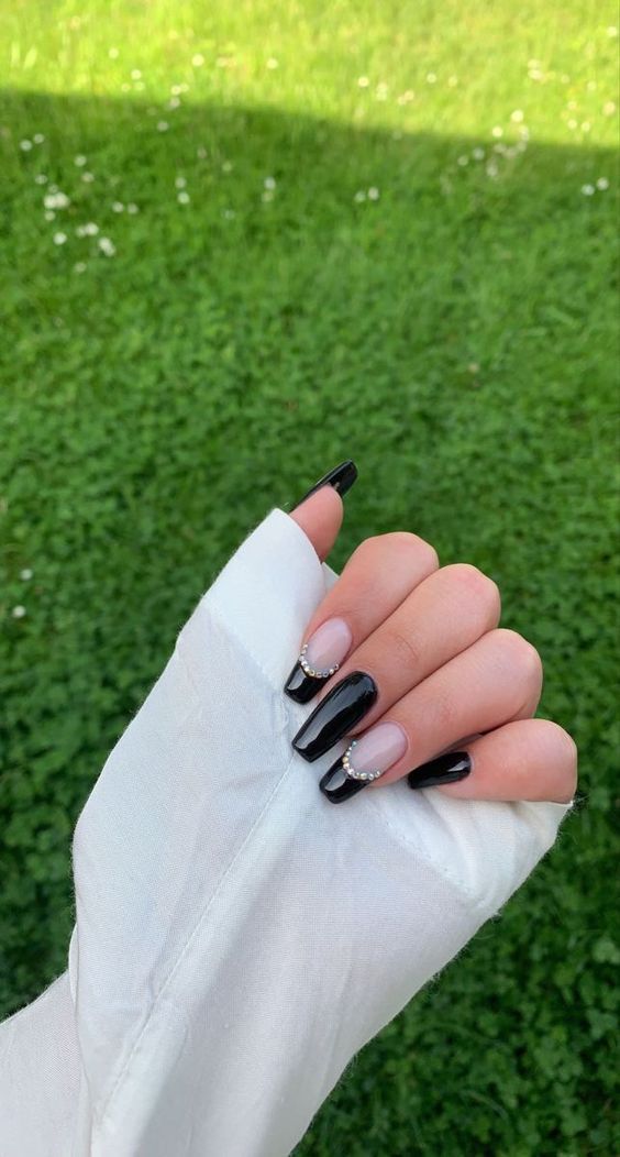 Chic Black and Nude Nail Design with Elegant Embellishments.