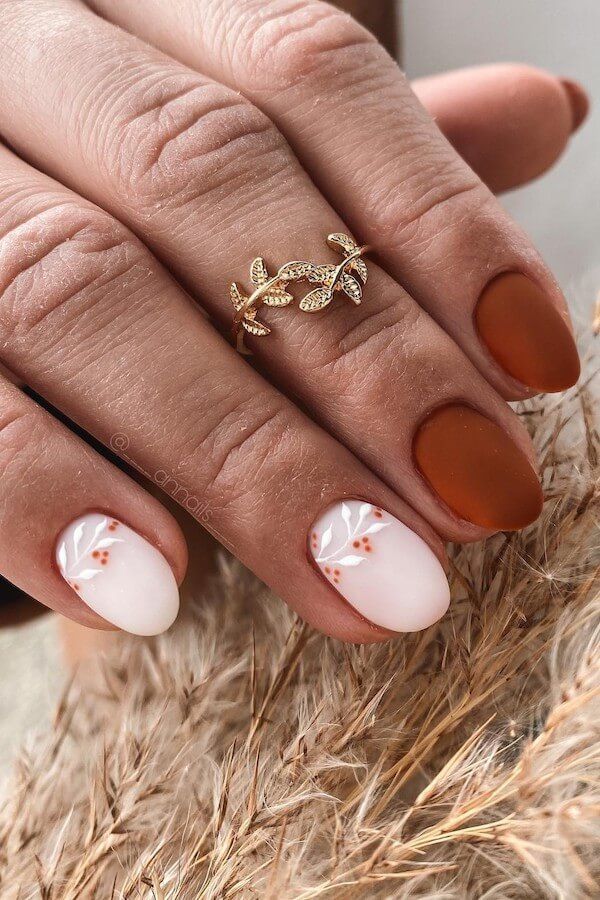 Chic Nail Design: Matte Brown and Glossy White with Elegant Floral Accents and Gold Ring