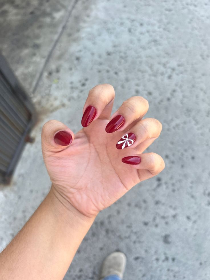 Chic Glossy Red Almond Nails with Elegant White Ribbon Design.