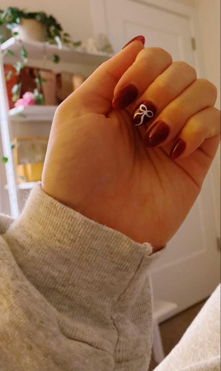 Sophisticated Burgundy Nail Design with Playful White Ribbon Detail