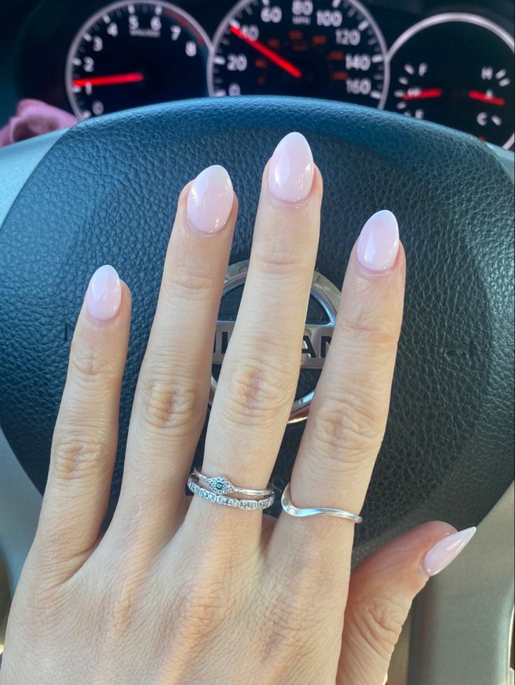 Sophisticated Soft Pink Oval Nails: Elegant Design with Glossy Finish and Chic Accessories.