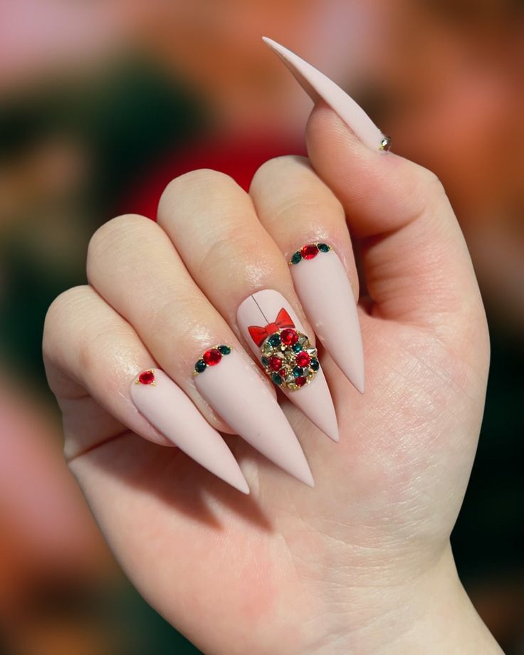 Elegant Stiletto Nail Design with Vibrant Holiday Jewels and Playful Bow Accent.