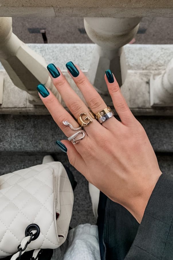 Sophisticated Deep Teal Nail Design with Stylish Rings for a Modern Look.