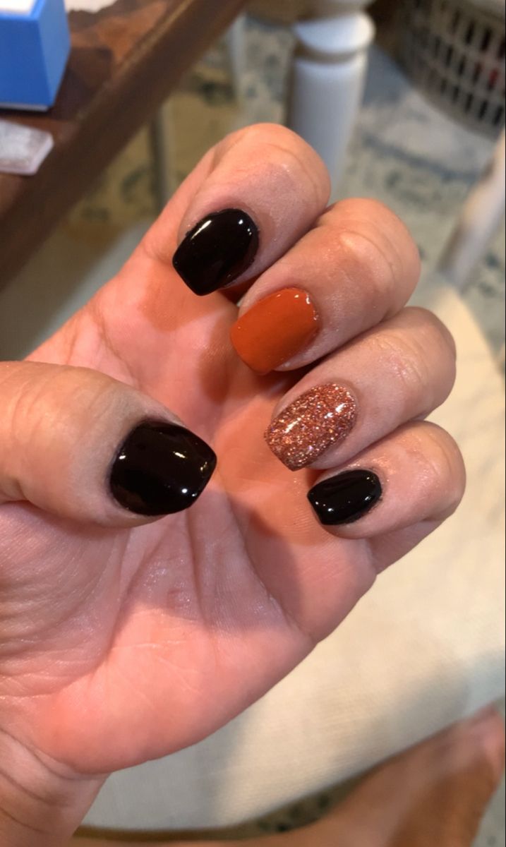 Festive Nail Design with Black, Orange, and Glitter Accents.