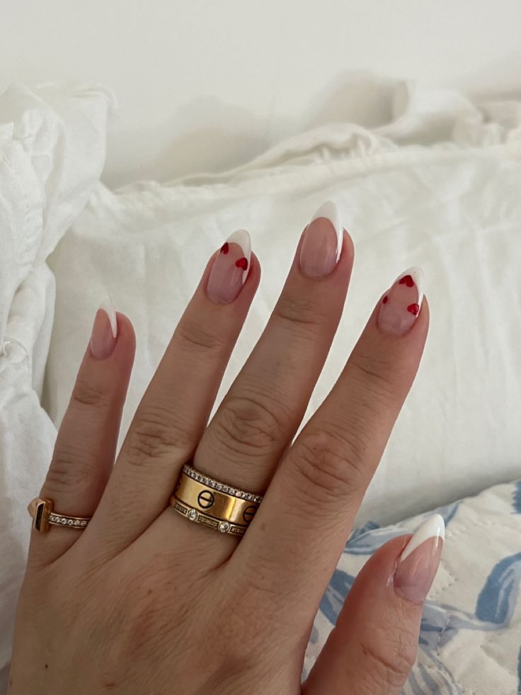 Elegant French Tip Manicure with Striking Red Hearts and Delicate Gold Accents.