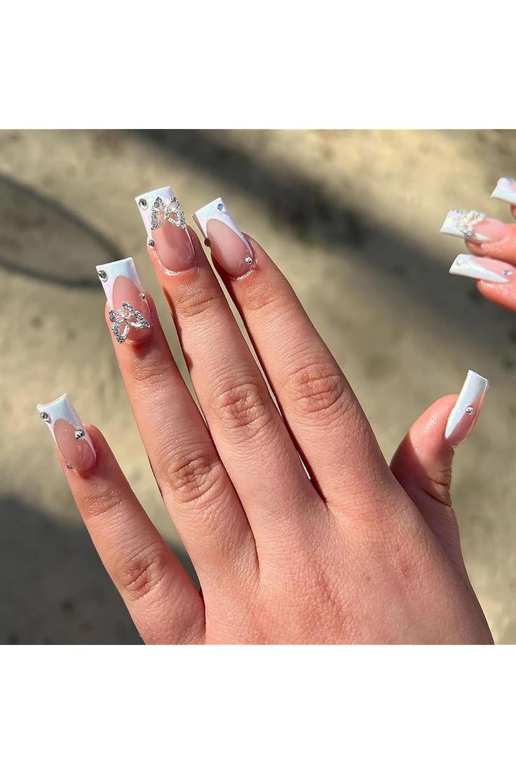 Sophisticated Nail Design: Glossy White Tips with Butterfly Embellishments and Rhinestones.