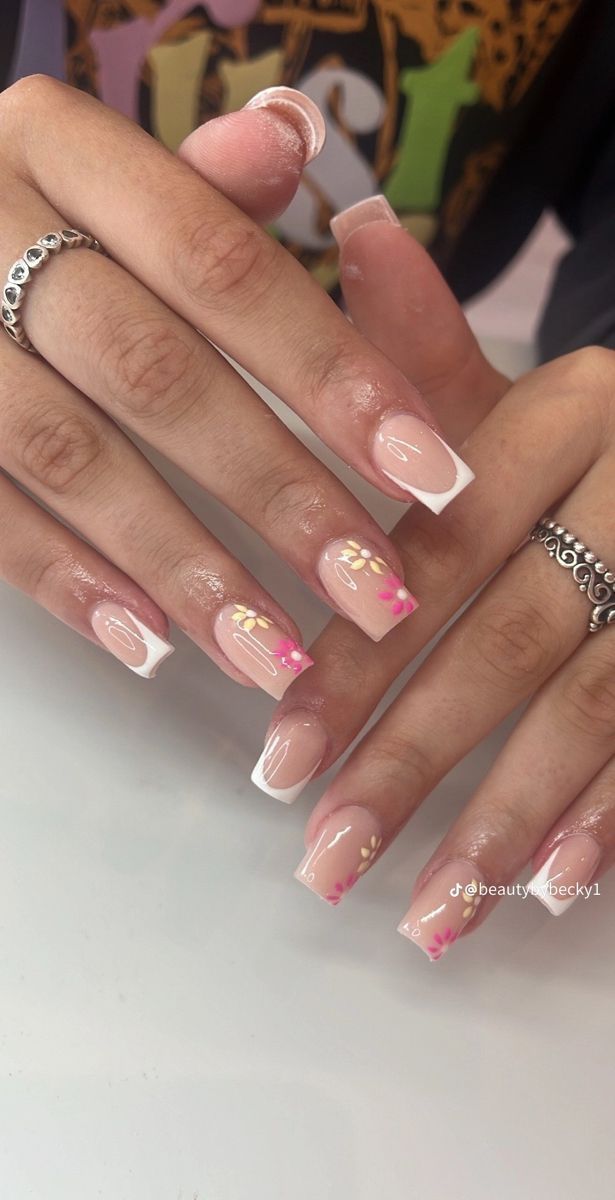 Sophisticated Nude French Tip Nails with Subtle Pink and Gold Floral Accents.