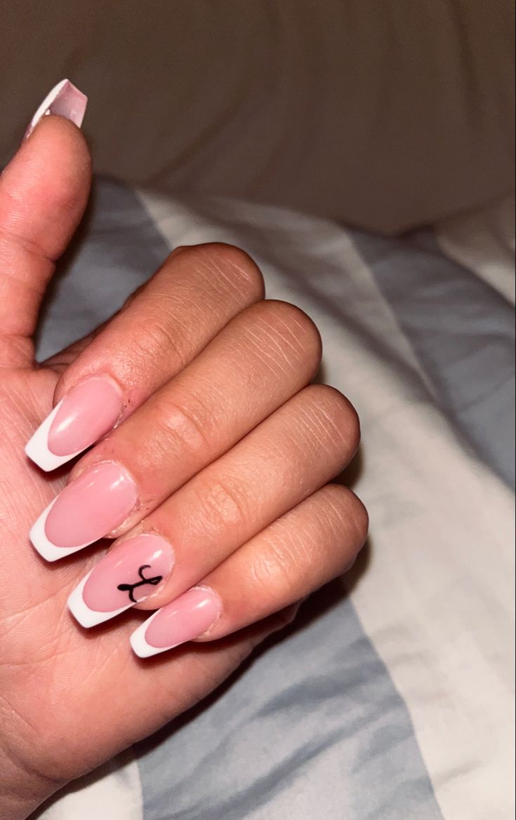 Modern French Tip Manicure: Pink Base, White Tips, and Playful Black Accent Design.