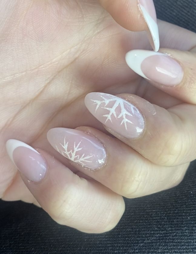 Elegant Winter Nail Design: Soft Nude Base with Delicate White French Tips and Snowflake Accents.