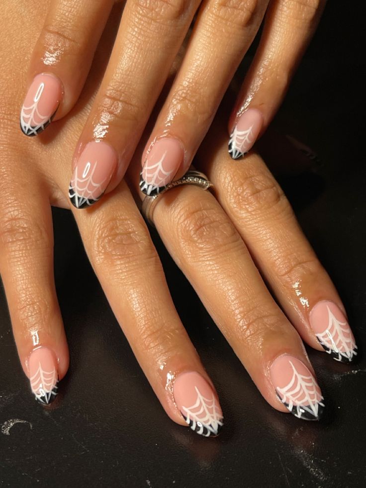 Chic Soft Pink and Black Nail Design with Intricate White Spider Web Accents.