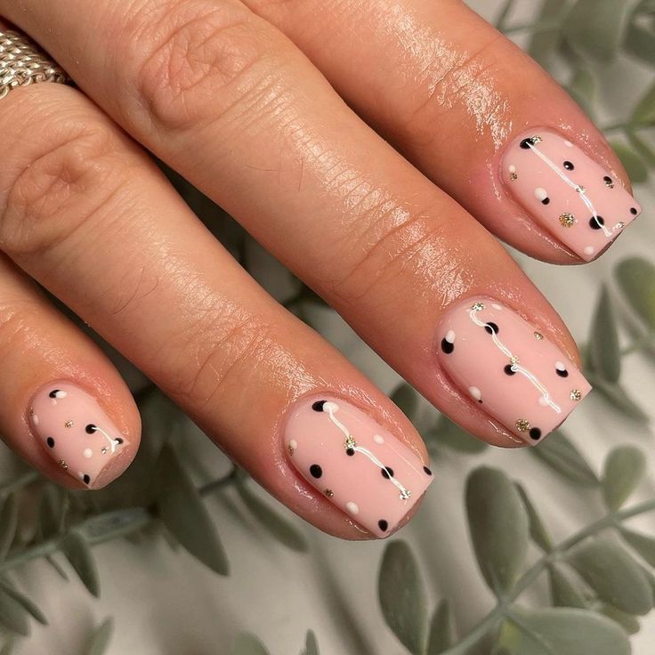 Elegant Chic Nail Design: Soft Pink Base with Black and White Dots and Gold Accents.