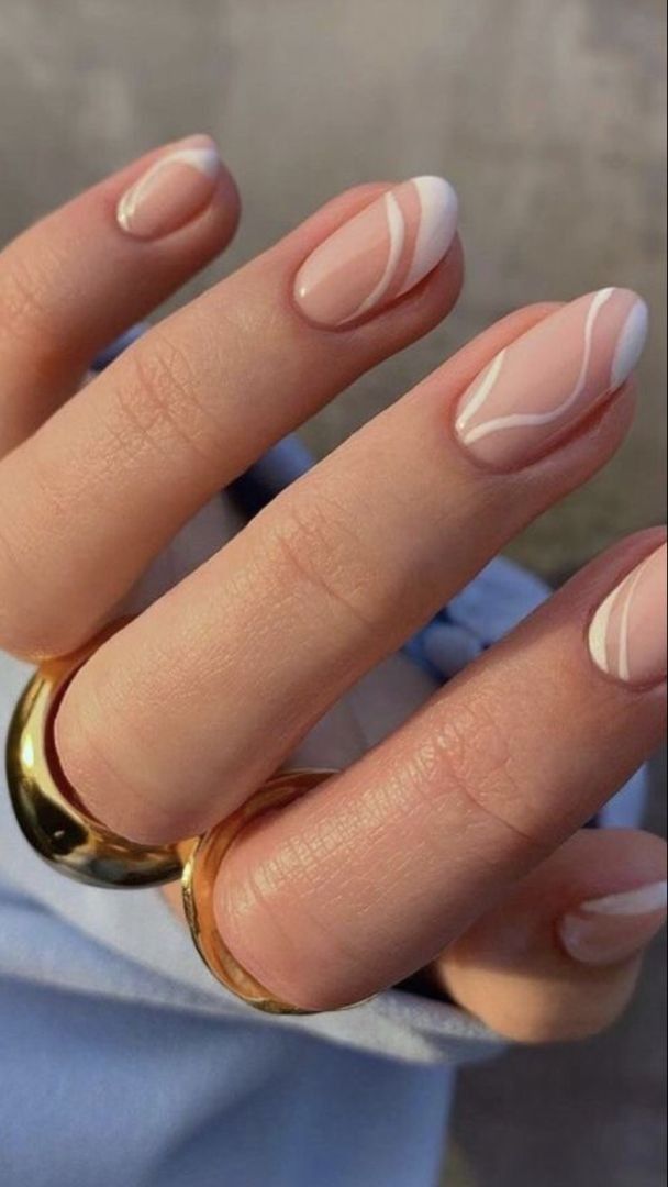 Chic Nail Design: Soft Nude Base with Artistic White Swirls and Gold Ring Accent.