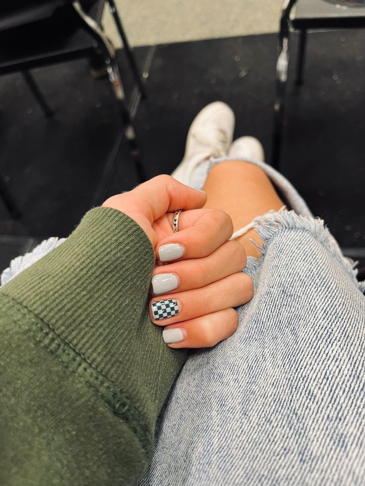 Chic Nail Art: Muted Gray Base with Playful Black-and-White Checkerboard Accent.