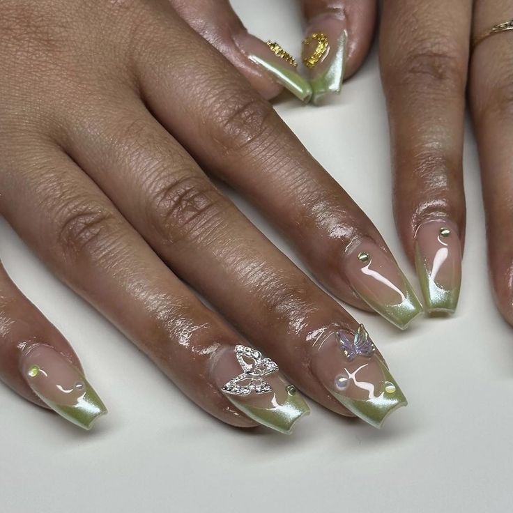 Chic Nail Design with Clear and Soft Green Colors Enhanced by Metallic Gold, Gems, and Leaf Motifs for a Sophisticated Look.