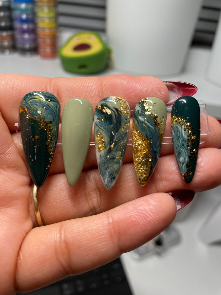 Chic Stiletto Nail Design Featuring Earthy Tones, Marble Patterns, and Glamorous Gold Flakes.