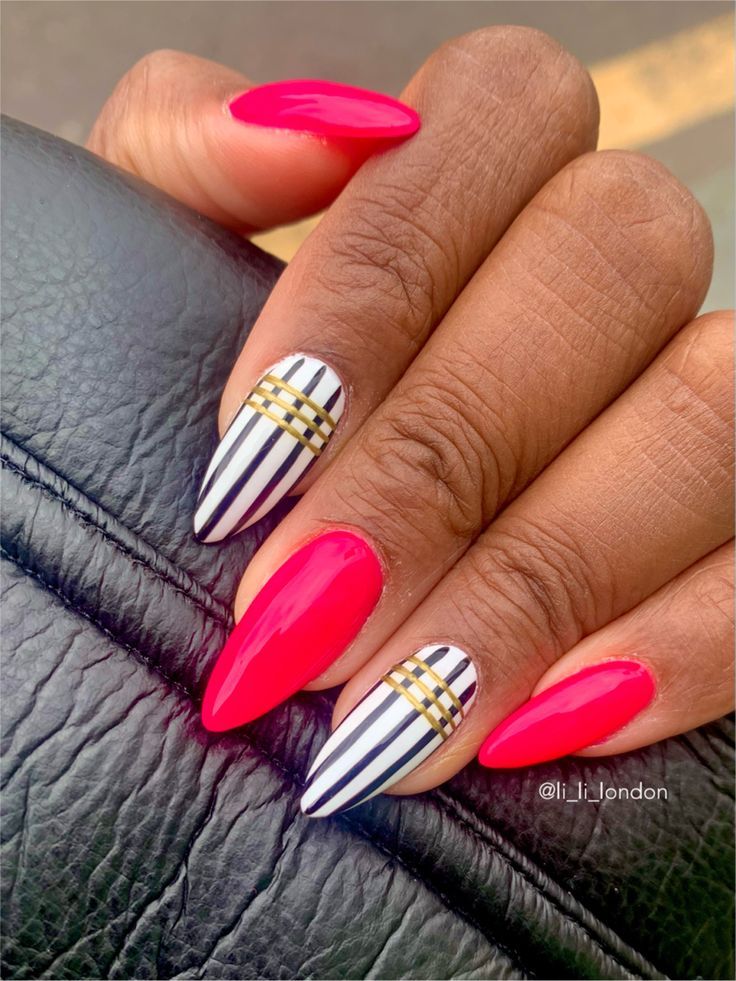 Chic Almond-Shaped Nail Design: Bold Pink with Black-and-White Stripes and Gold Accents.