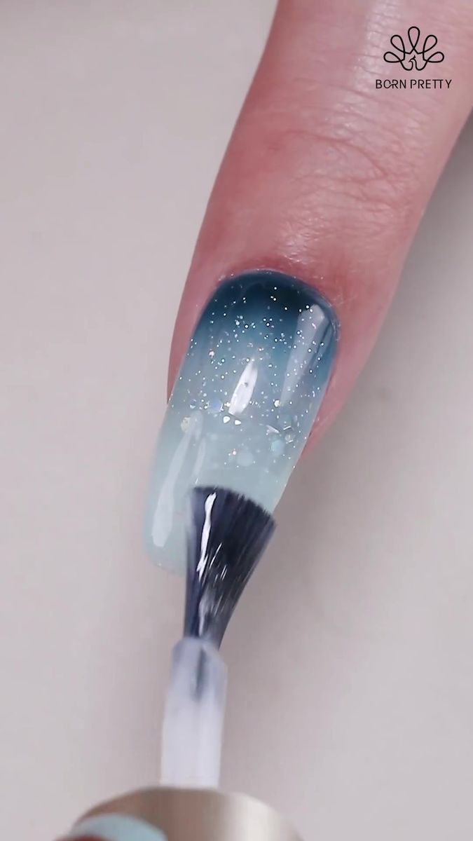 Elegant Ombre Nail Design: Gradient Blue with Shimmering Sparkle.