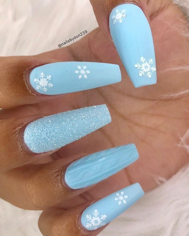 Winter-Themed Nail Design Showcasing Light Blue Shades and Snowflake Accents with Matte and Glitter Textures.