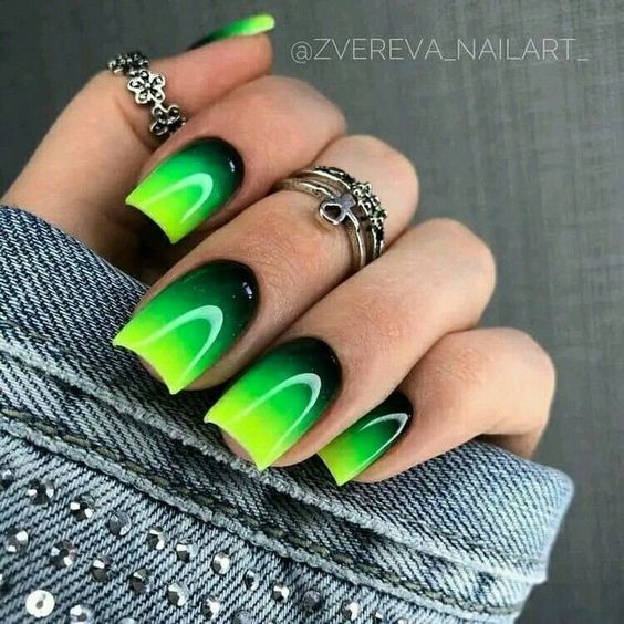 Vibrant Green and Black Gradient Nail Design with Elegant Curvy Lines and Textured Denim Backdrop.