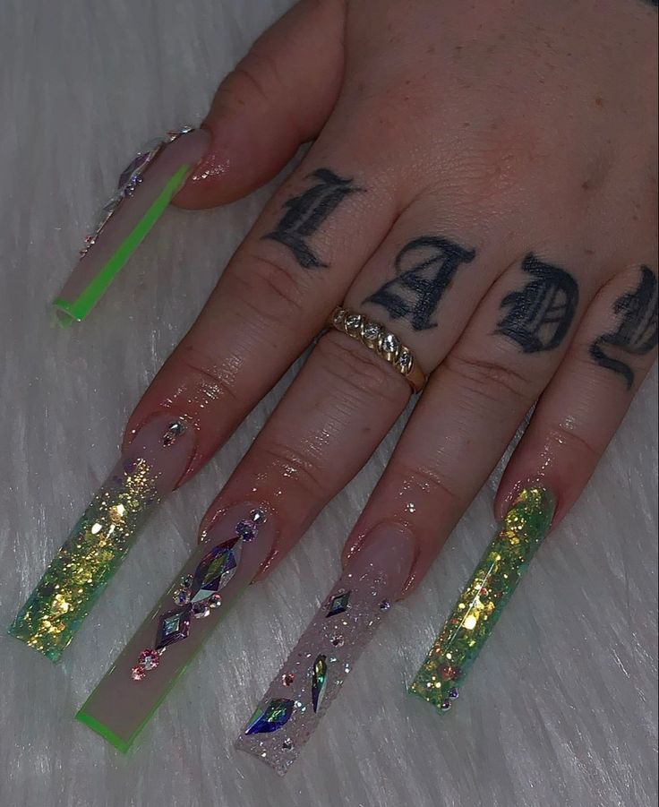 Striking Bold Nail Design with Long Square Tips, Vibrant Colors, Glitter, and Gem Embellishments.