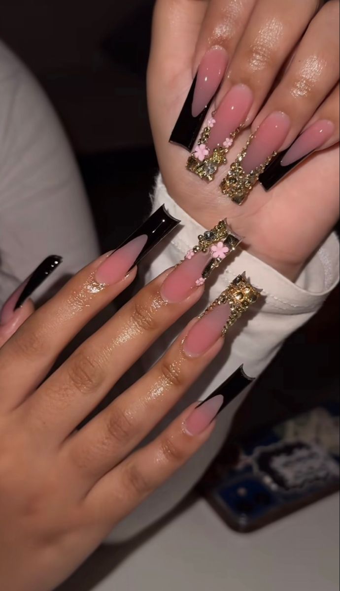 Luxurious Soft Pink and Black Nail Design with Gold and Floral Accents for a Bold Feminine Look.