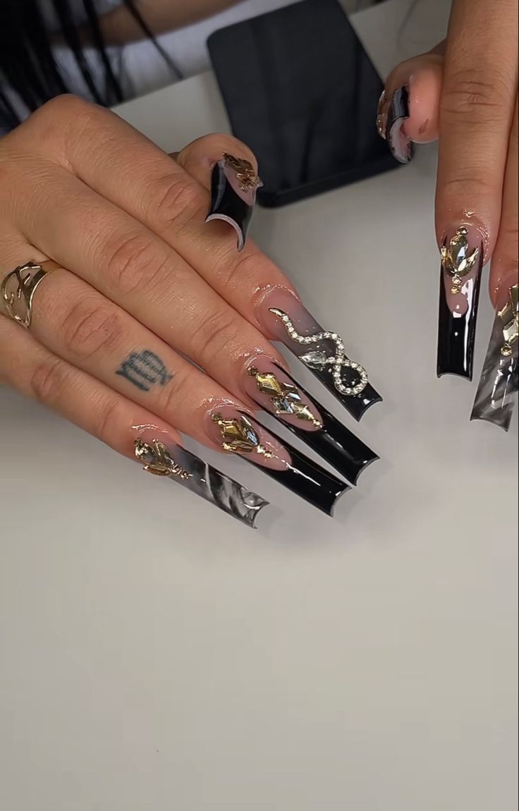 Dramatic Long Nail Design: Glossy Black and Nude Tones with Edgy Metallic Accents and Sparkling Snake Motif.