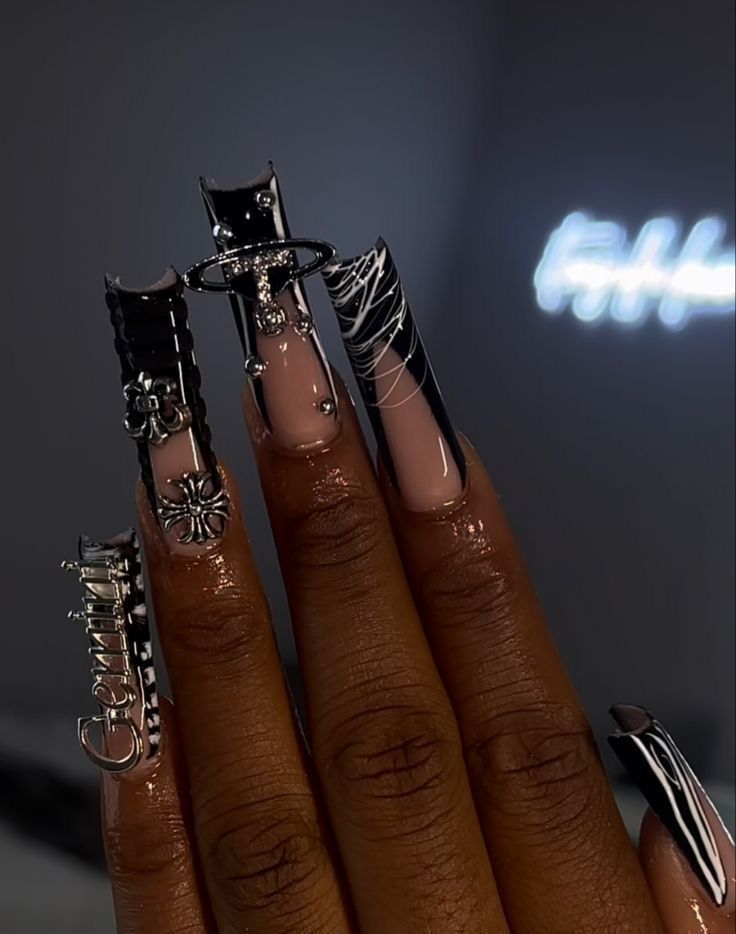 Bold Acrylic Nail Design Blending Metallic Embellishments with Soft Nude and Striking Black and White Patterns.