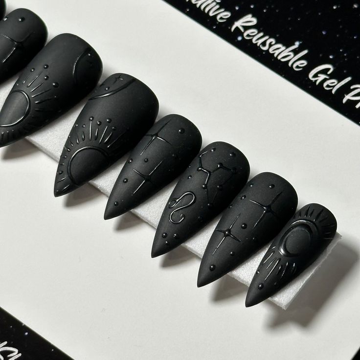 Cosmic-Inspired Futuristic Nail Design: Matte Black Stiletto with Intricate Geometric Patterns.