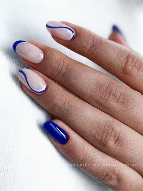 Elegant Nude and Bold Blue Gradient Nail Design with Delicate Curved Lines.