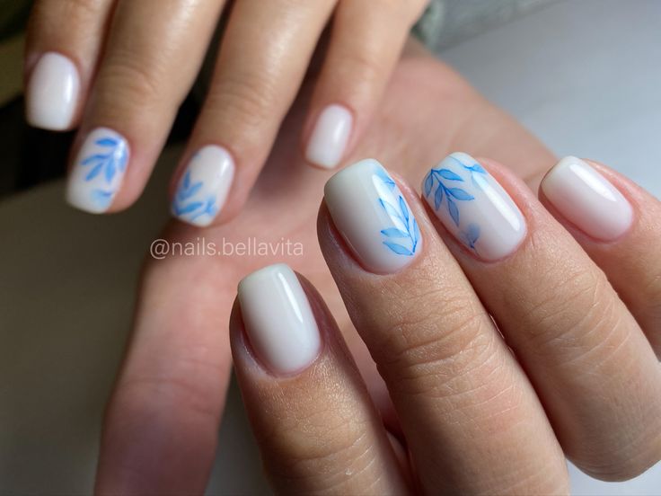 Elegant Nail Design: Soft White Base with Delicate Blue Leaf Patterns for a Fresh Look.