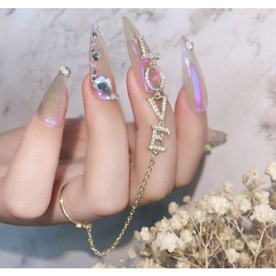 Iridescent Glam Nail Design with Rhinestones and Trendy Chain Accents.