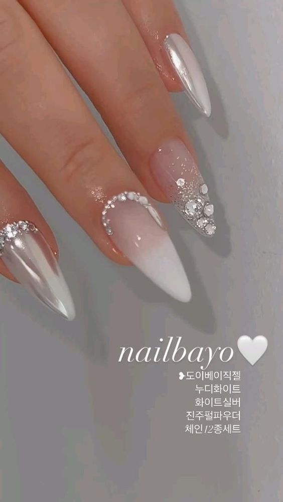 Sophisticated Elegant Nail Design: Soft White and Nude Shades with Glamorous Embellishments.