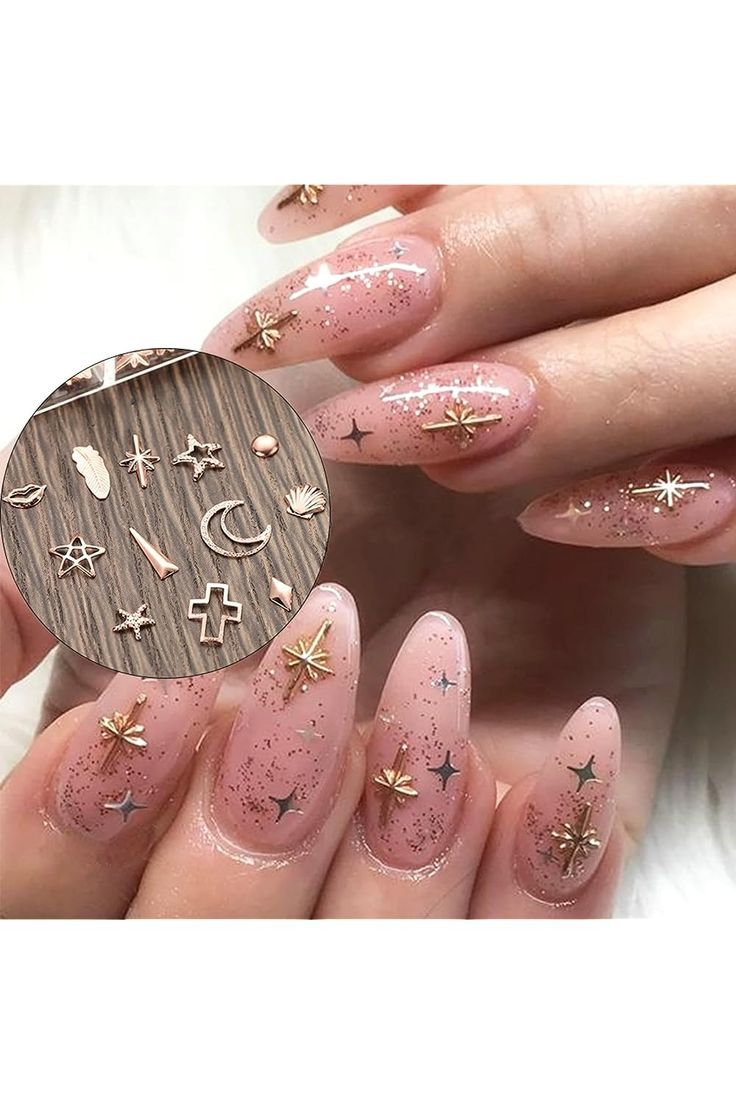 Whimsical Elegance: Soft Nude Nails with Shimmering Glitter and Metallic Gold Charms.