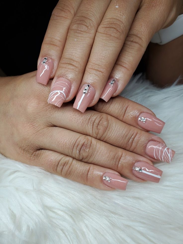 Sophisticated Elegance: Nude Nails with Delicate White Swirls and Glamorous Rhinestones