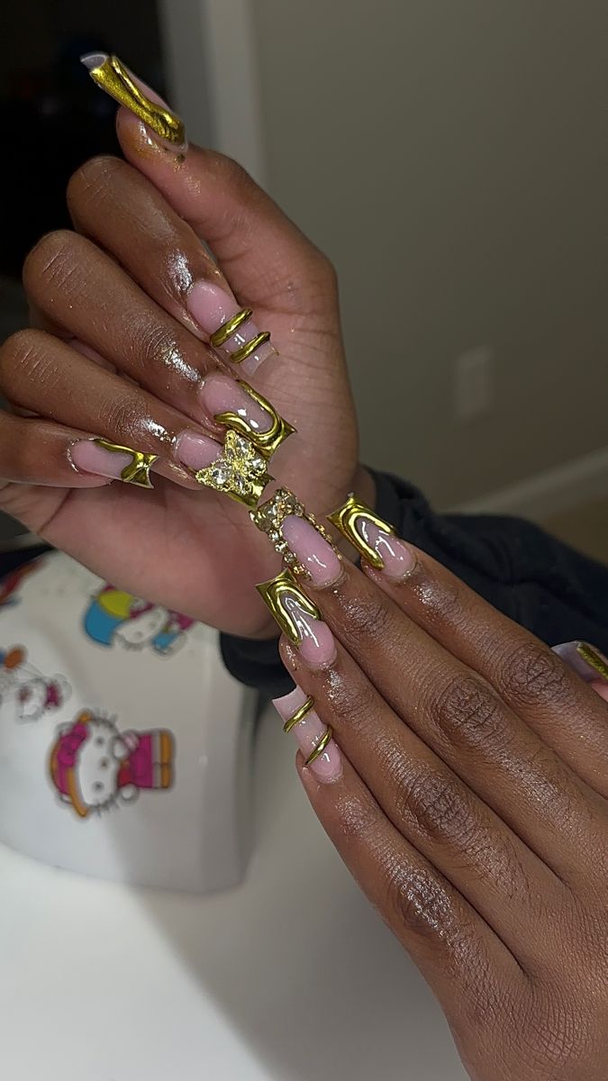 Chic Nail Design: Elongated Tips with Gold Accents and Playful Motifs.