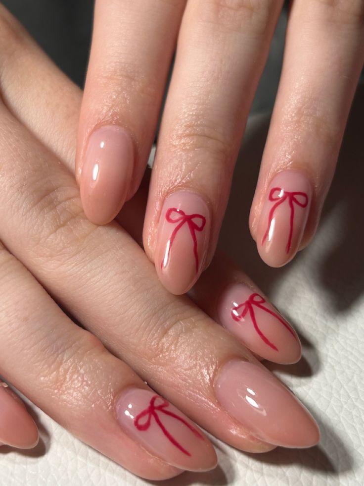 Elegant Nude Nail Design with Playful Red Bow Accents