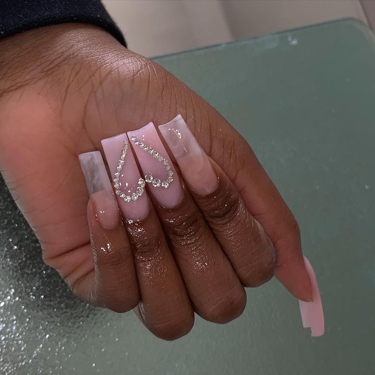 Chic Soft Pink Nail Design with Rhinestone Heart Accents for Glamorous Style.