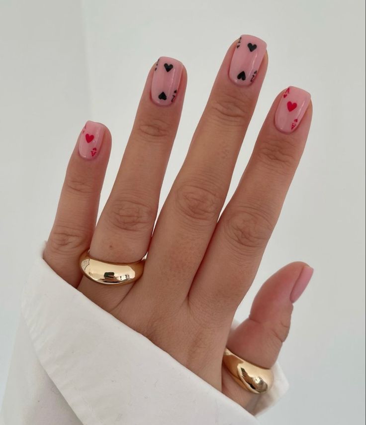 Chic Pink Nail Design with Playful Heart Motifs and Elegant Gold Accents.