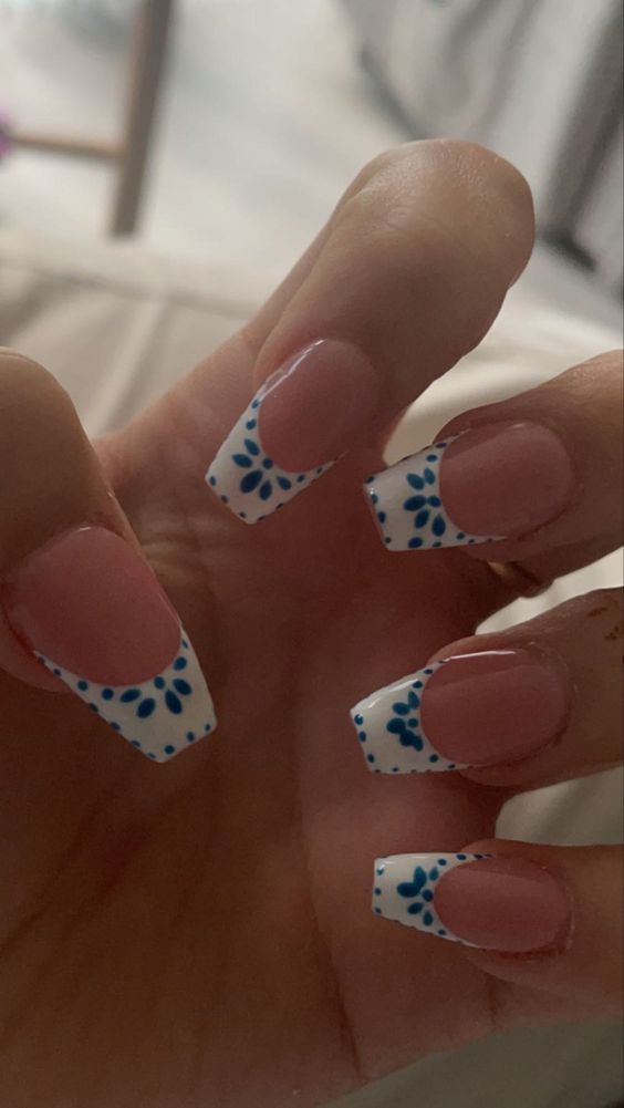 Chic French Tip Nails with Delicate Blue Floral Accents for a Fun, Sophisticated Look.