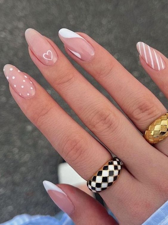 Chic Pink and White Nail Design with Polka Dots, Stripes, and Heart Motif, Accented by Elegant Rings.