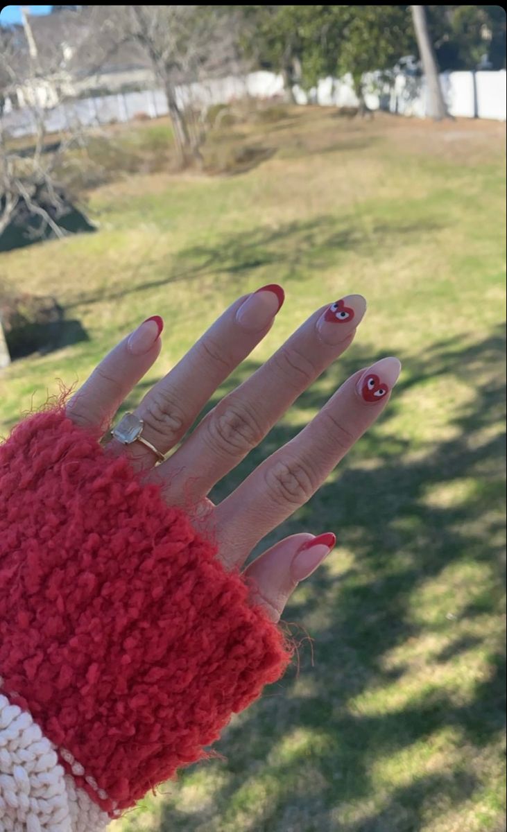 Elegant Playful French Tip Nail Design with Vibrant Red Tips and Hand-Painted Embellishments.