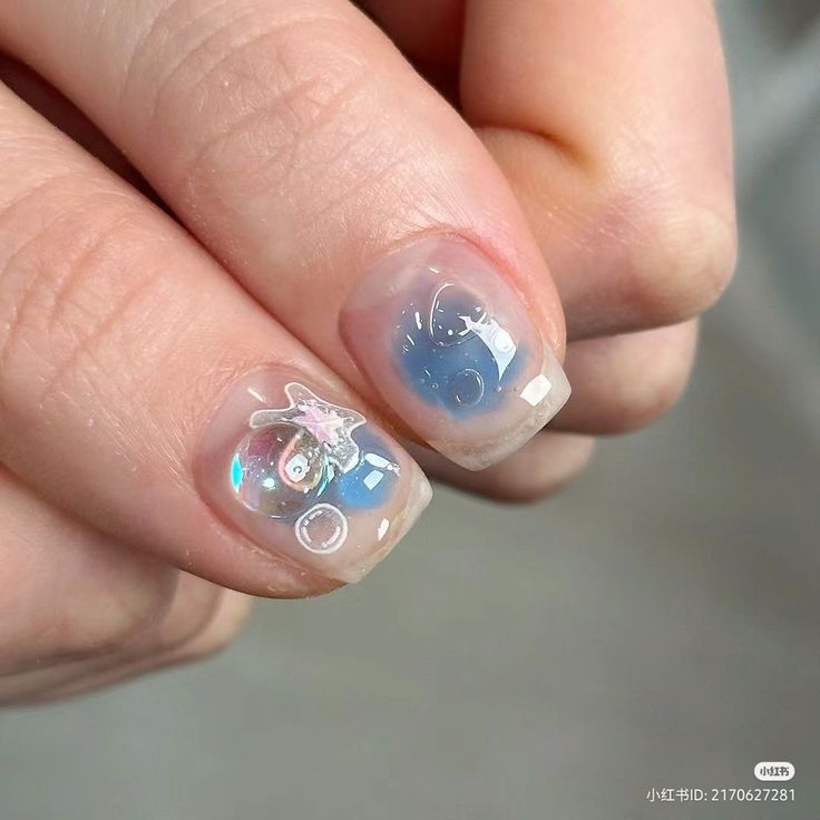 Playful Whimsical Nail Design with Soft Blue Gradient and Cartoon Motifs.