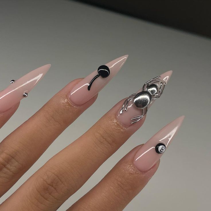 Chic Nail Design: Elongated Tips with Nude Base, Metallic Spider Embellishments, and Edgy Accents.