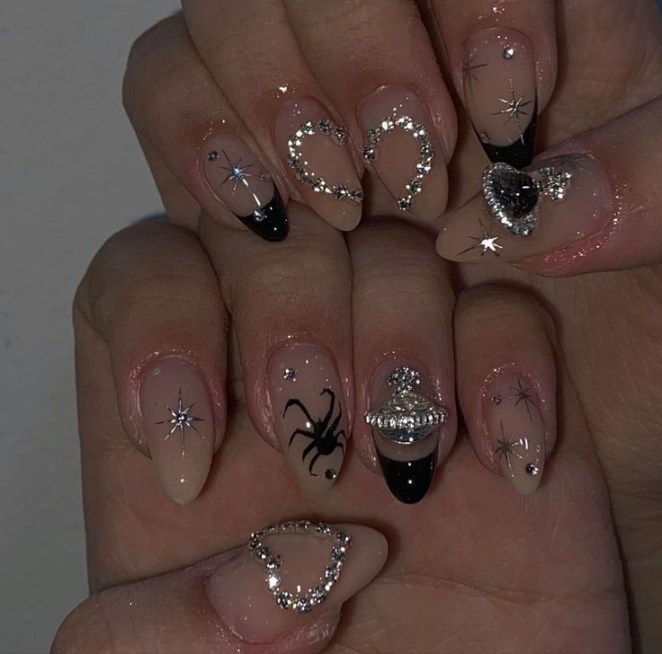 Chic Nail Art: Nude and Black Design with Glittering Embellishments and Playful Spider Motif.