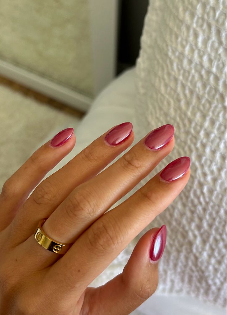 Elegantly Polished Burgundy Oval Nails with Glossy Finish and Gold Ring Accent.