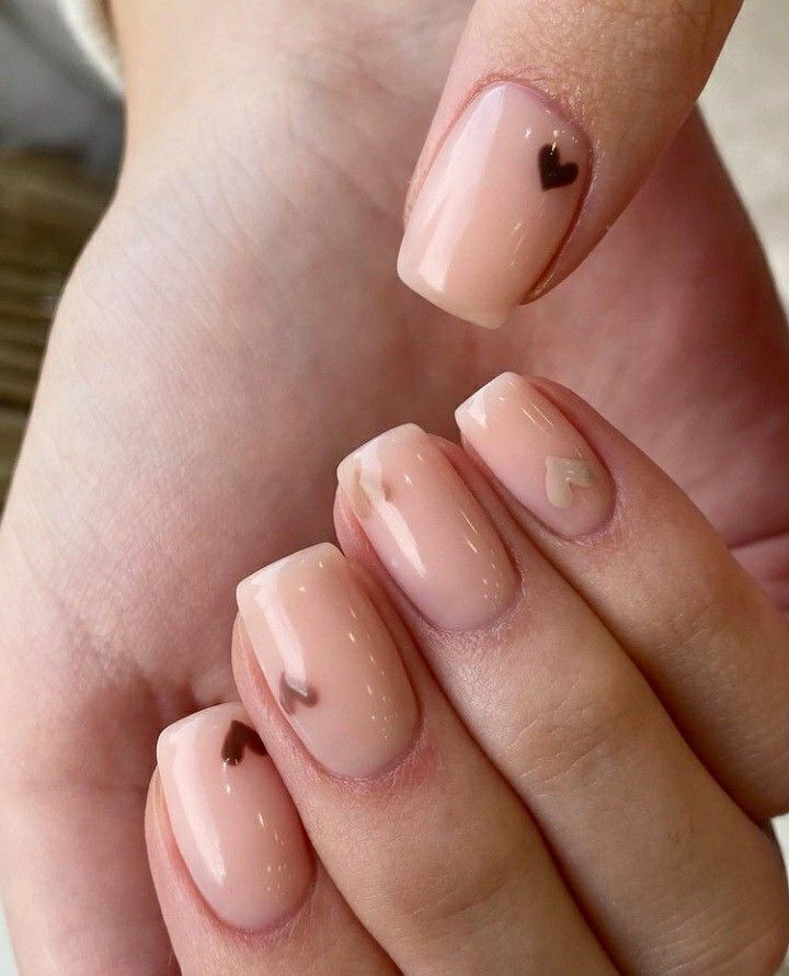 Chic Nude Nail Design with Delicate Heart Accents for a Romantic Touch.