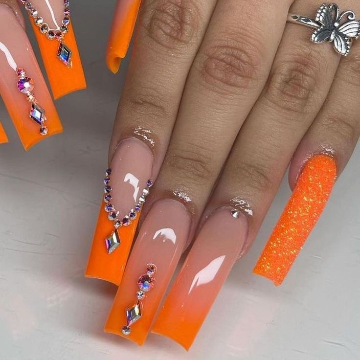 Striking Orange and Nude Gradient Nails with Rhinestones for a Glamorous Statement Look.