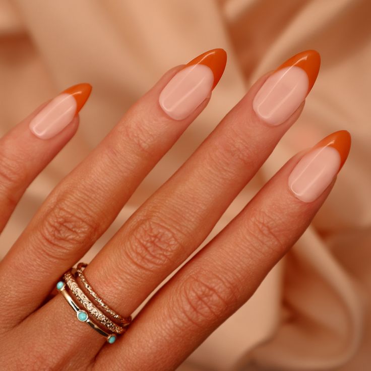 Chic Almond-Shaped Nails: Elegant Nude Base with Vibrant Orange Tips for a Stylish Statement.