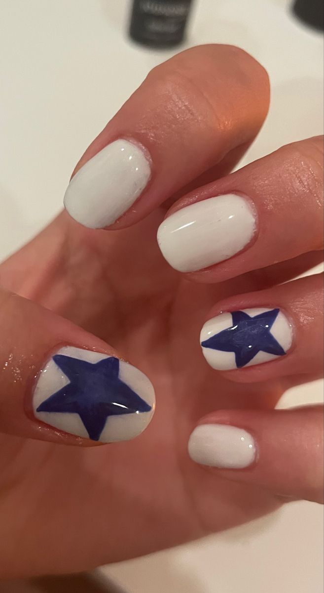 Chic Nail Design: Classic White Base with Bold Blue Star Patterns.